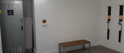 Una habitación con un banco, una puerta con panel de seguridad y un aplique.