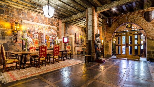 A dining area with a stone wall, wooden ceiling, and a large arched doorway. - Hotel Temple Ponferrada (Ponferrada)