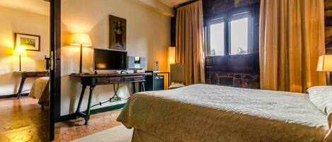 Una habitación de hotel con una cama grande, un escritorio con computadora, una silla y televisión.