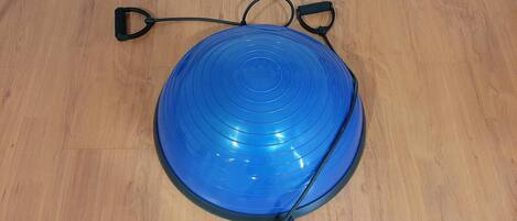 A blue exercise ball with a handle on a wooden floor.