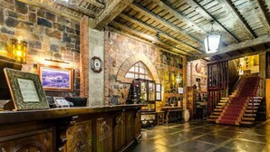A spacious lobby with a stone wall, wooden reception desk, and a staircase leading to upper floors. - Hotel Temple Ponferrada (Ponferrada)