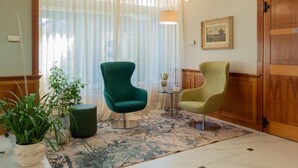 Une pièce avec deux chaises, une table, une lampe, une plante en pot et une porte en bois.