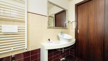 Un baño con lavamanos blanco, un espejo, toallero y puerta de madera.