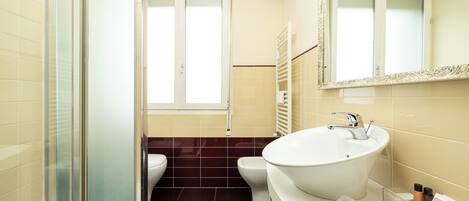 A modern bathroom with a glass shower enclosure, a white sink, and a toilet.