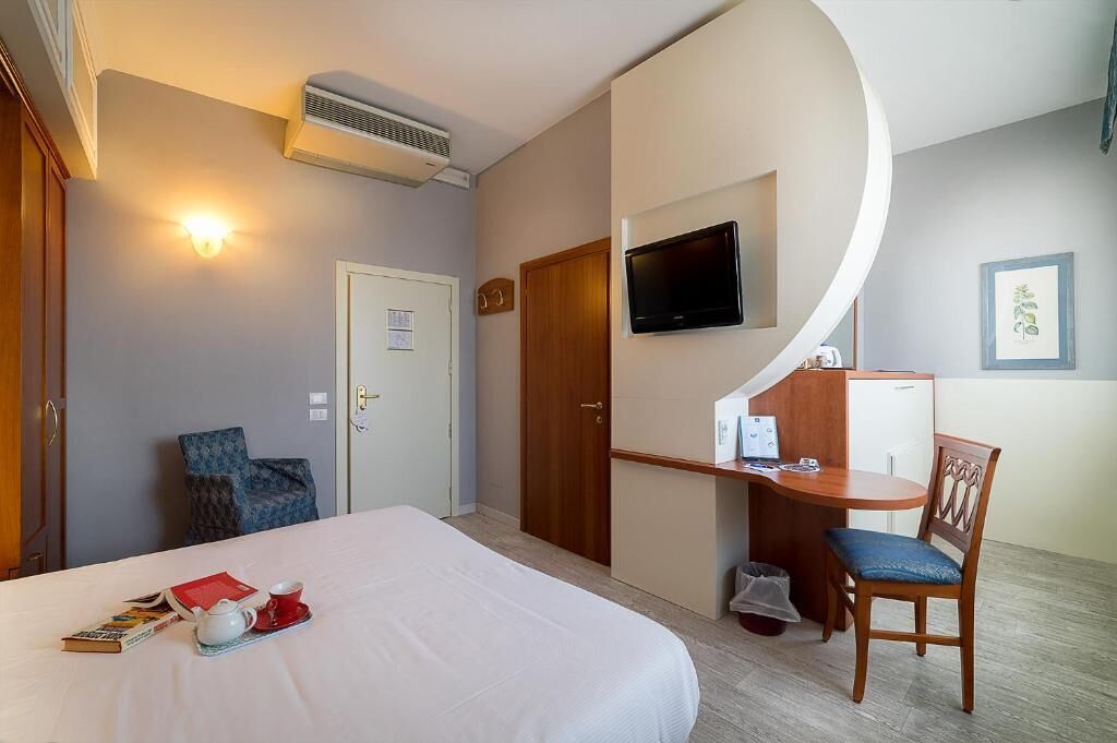 Une chambre d’hôtel comprenant un lit, un bureau avec une chaise, une télévision et un petit placard.