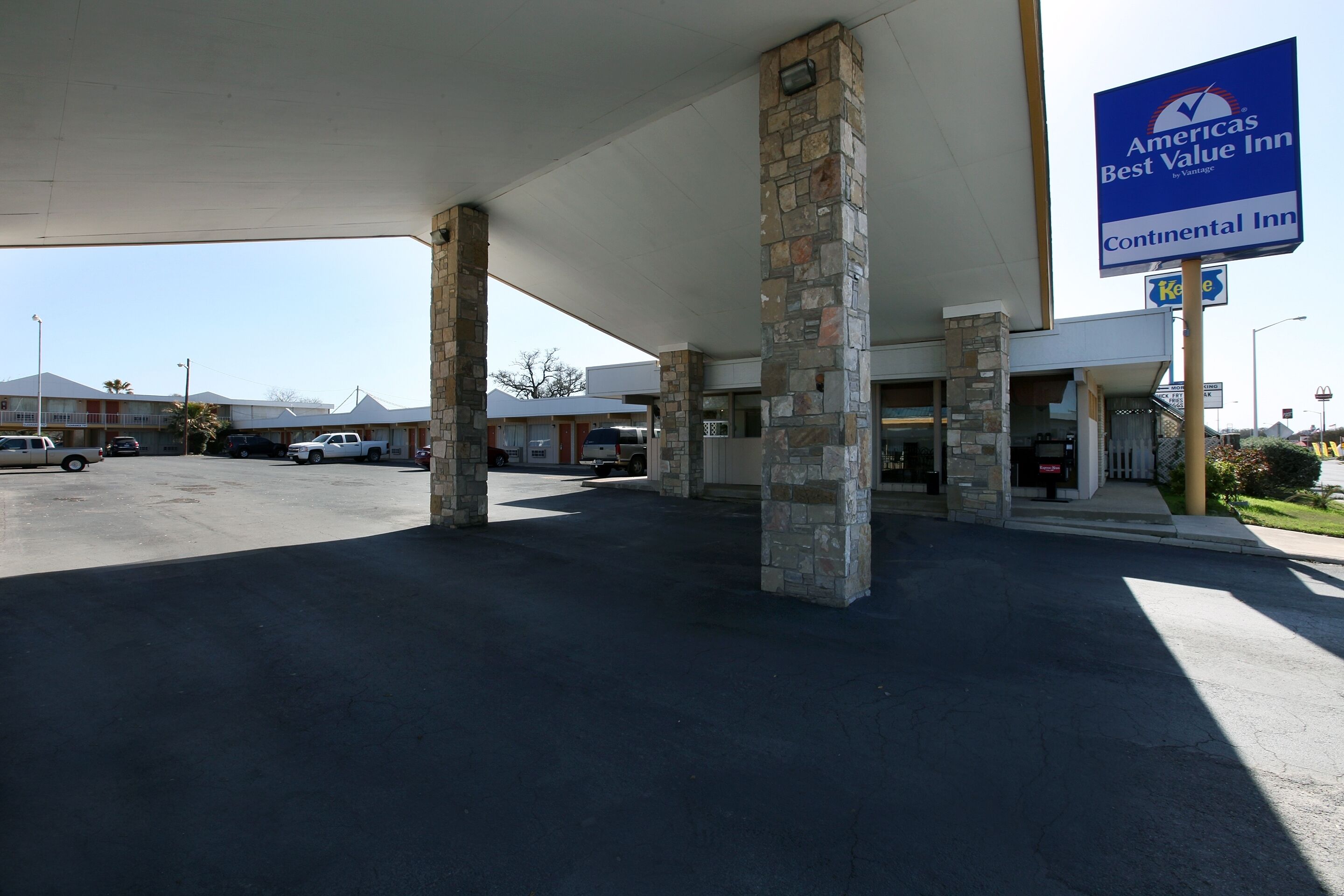 A Continental Inn with a stone pillar entrance, a parking lot, and a clear view of the surrounding area including other buildings and a McDonald's.