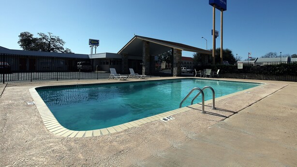 A swimming pool with a covered area, lounge chairs, and a sign for 'Kettle's Best Value Inn'.