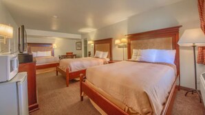 A hotel room with two beds, a desk, a chair, and a lamp. - Americas Best Value Inn Uvalde (Uvalde)