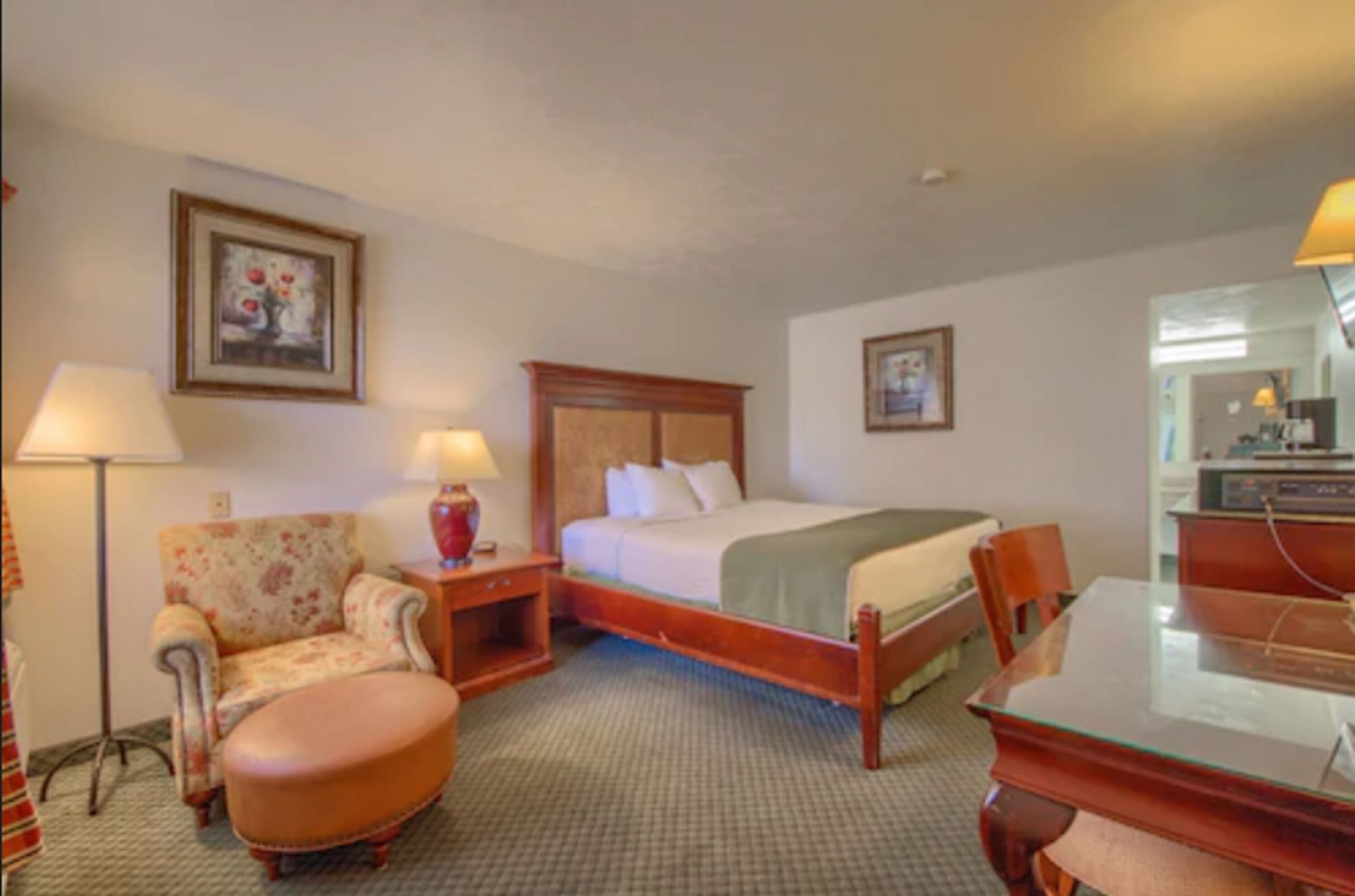 Una habitación de hotel con una cama, una silla, un escritorio y una lámpara.