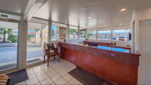 A reception area with a counter, a bench, and a view of the street outside. - Americas Best Value Inn Uvalde (Uvalde)