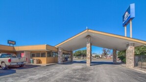 A gas station with a canopy, a truck, and a building with a sign. - Americas Best Value Inn Uvalde (Uvalde)