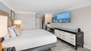 Una habitación de hotel moderna con una cama grande, un televisor de pantalla plana, un escritorio con una silla y un armario.