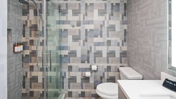 A modern bathroom with a shower, toilet, and sink.