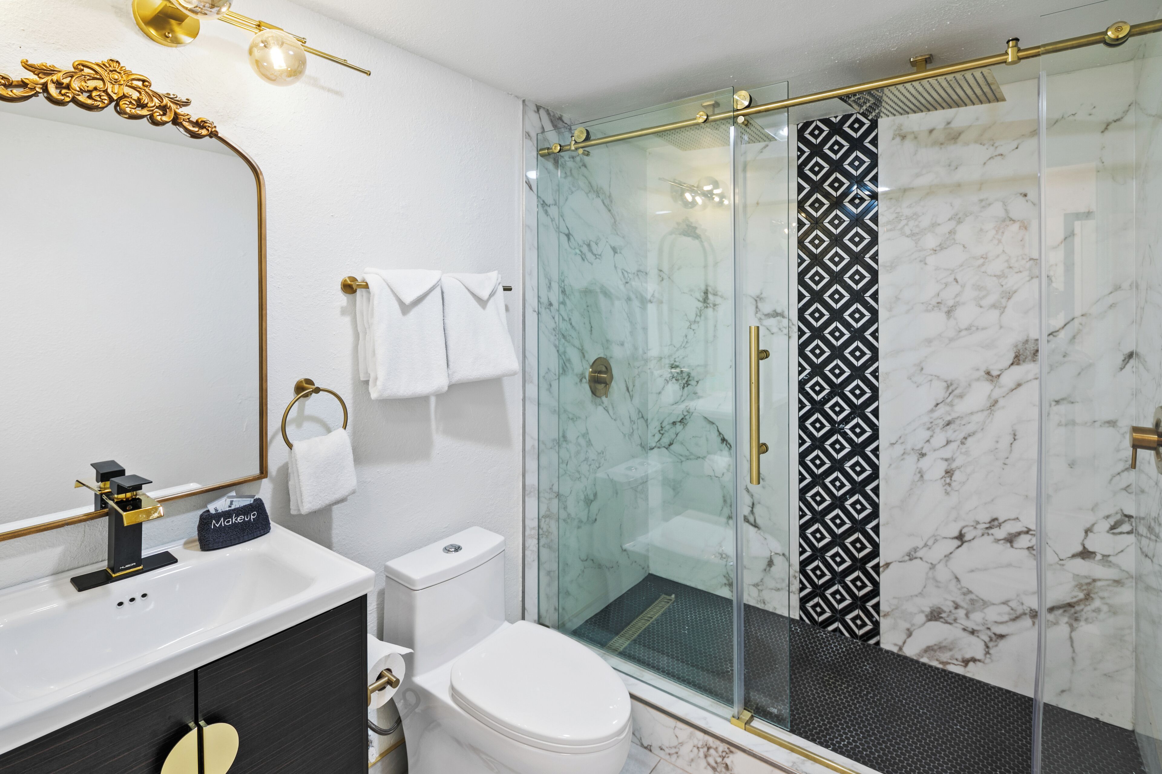 A modern bathroom with a glass-enclosed shower, a white sink, and a black vanity.