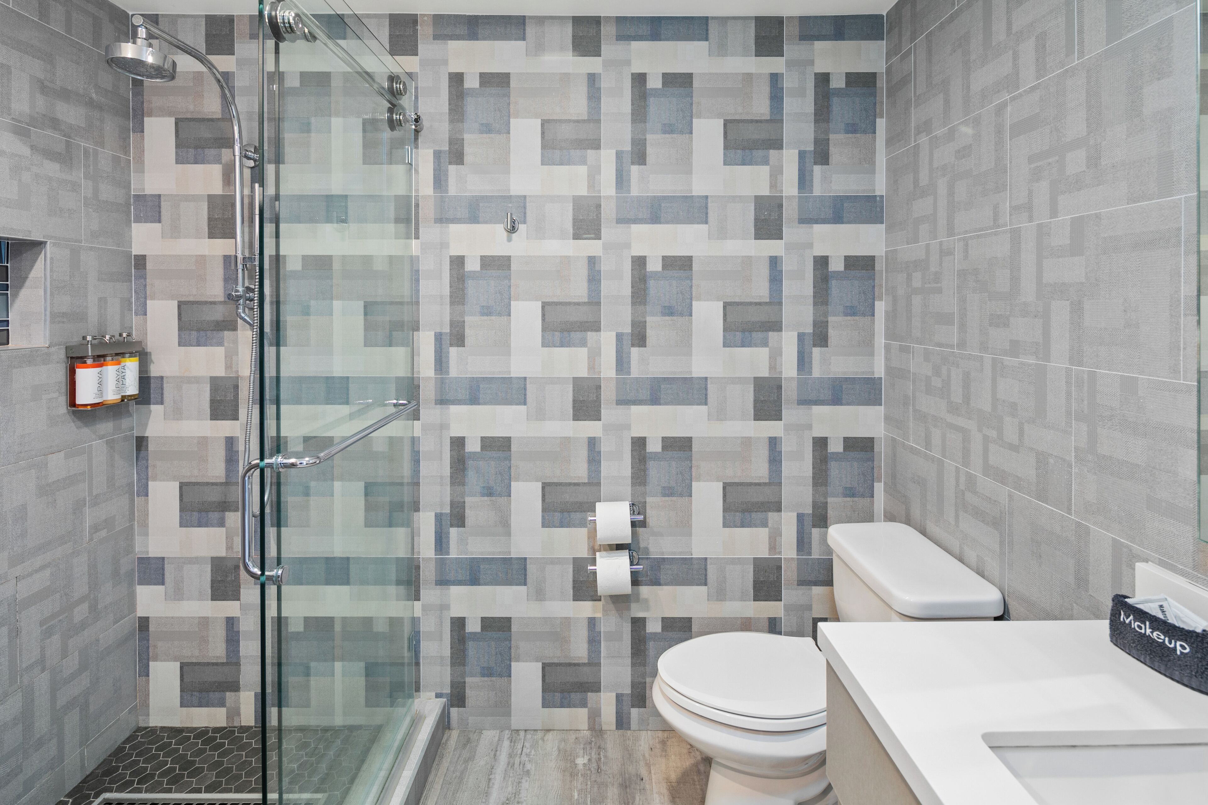 A modern bathroom with a shower, toilet, and sink.