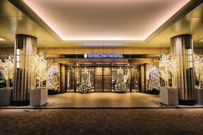 The entrance of Intercontinental hotel with a modern facade, large glass doors, and symmetrical white Christmas trees. - InterContinental Tokyo Bay by IHG (Tokyo)