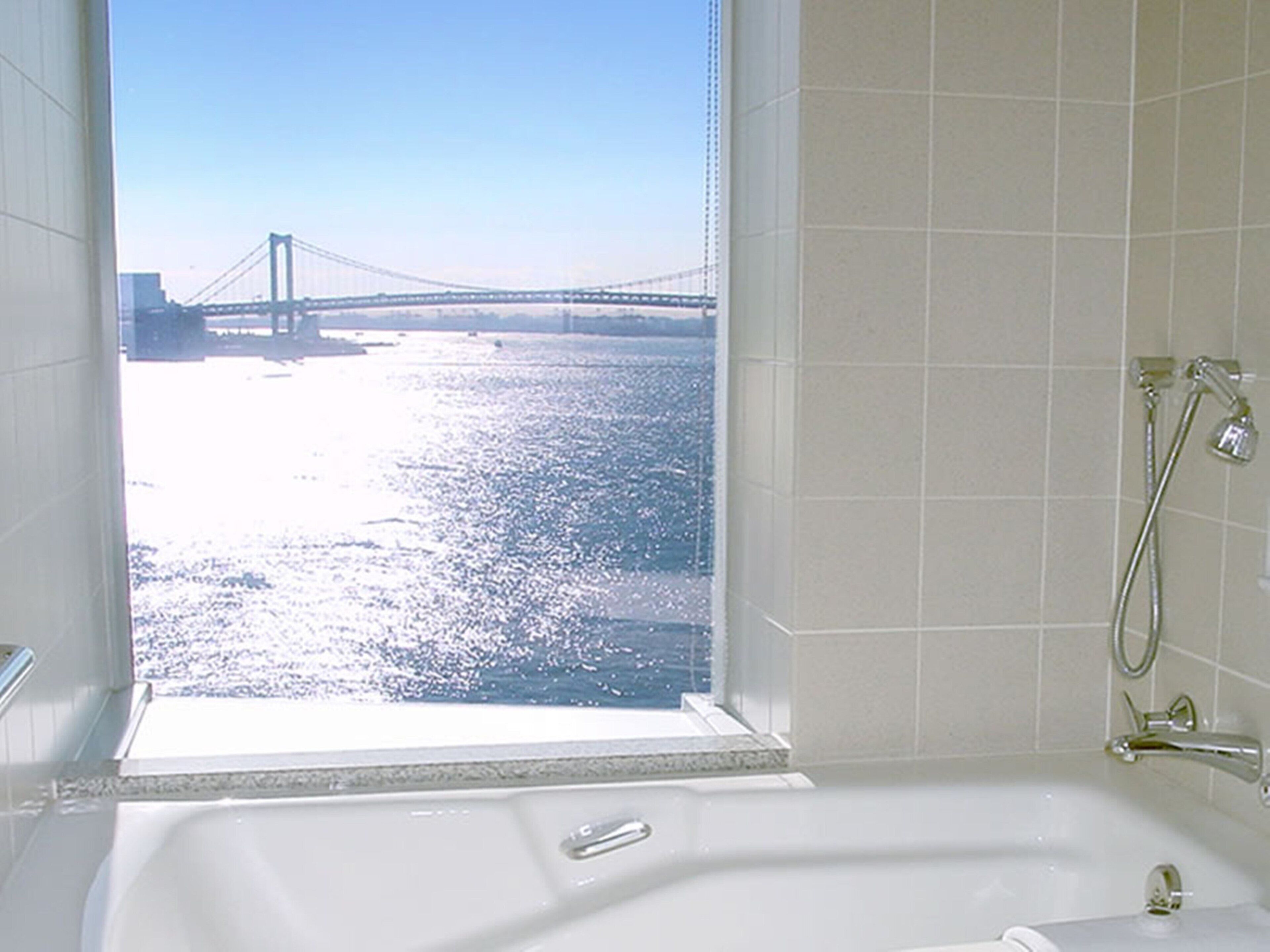 A bathroom with a large window, a bathtub, and a shower.