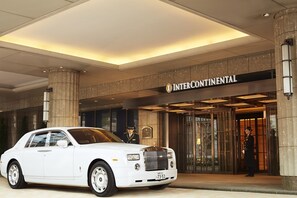 A white luxury car parked in front of the Intercontinental hotel entrance.