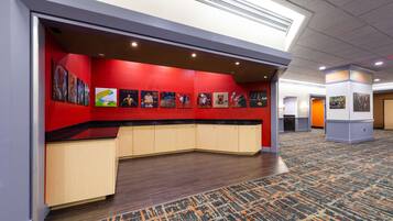 A hotel lobby with a red accent wall, a curved reception desk, and a patterned carpet.