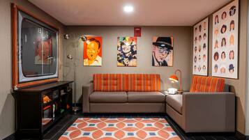 Relax in this stylish living room with a large flat-screen TV, comfortable sofa, and artwork-adorned walls.