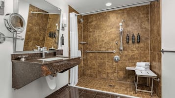 A modern bathroom with a shower, a sink with a mirror, and toiletries on the wall.
