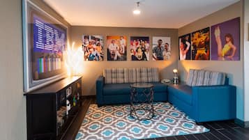 A living room with a blue sofa, a coffee table, a TV, and framed pictures on the wall.