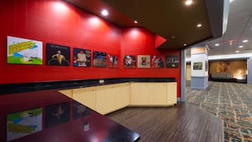 Un vestíbulo de hotel con una pared roja, un mostrador de recepción negro y una alfombra estampada.