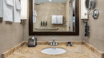 Un baño con lavamanos de encimera de granito, un espejo grande y un perchero para toallas.
