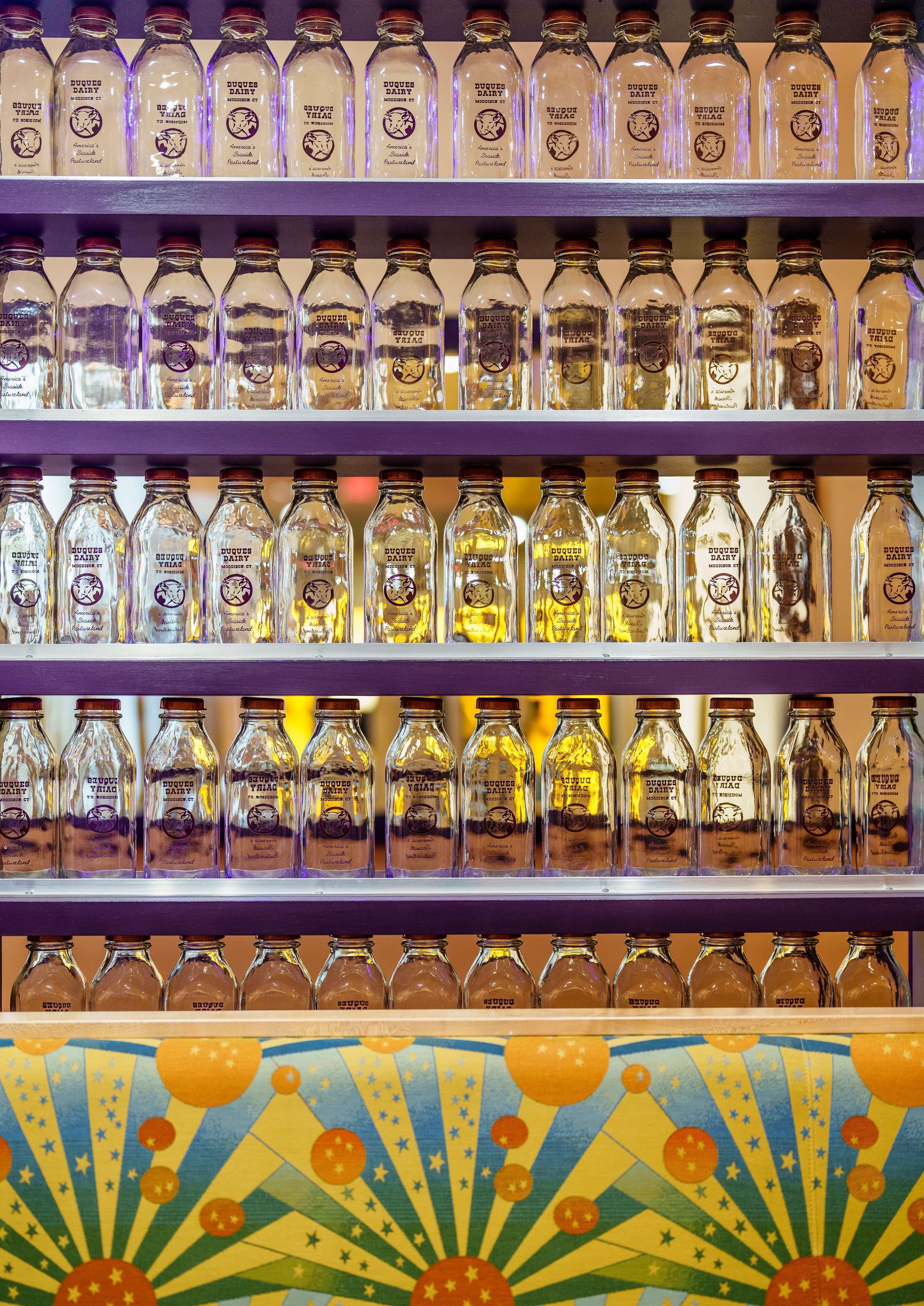 Shelves of bottles labeled 'SUGAR DAIRY' with a colorful, patterned design at the bottom.