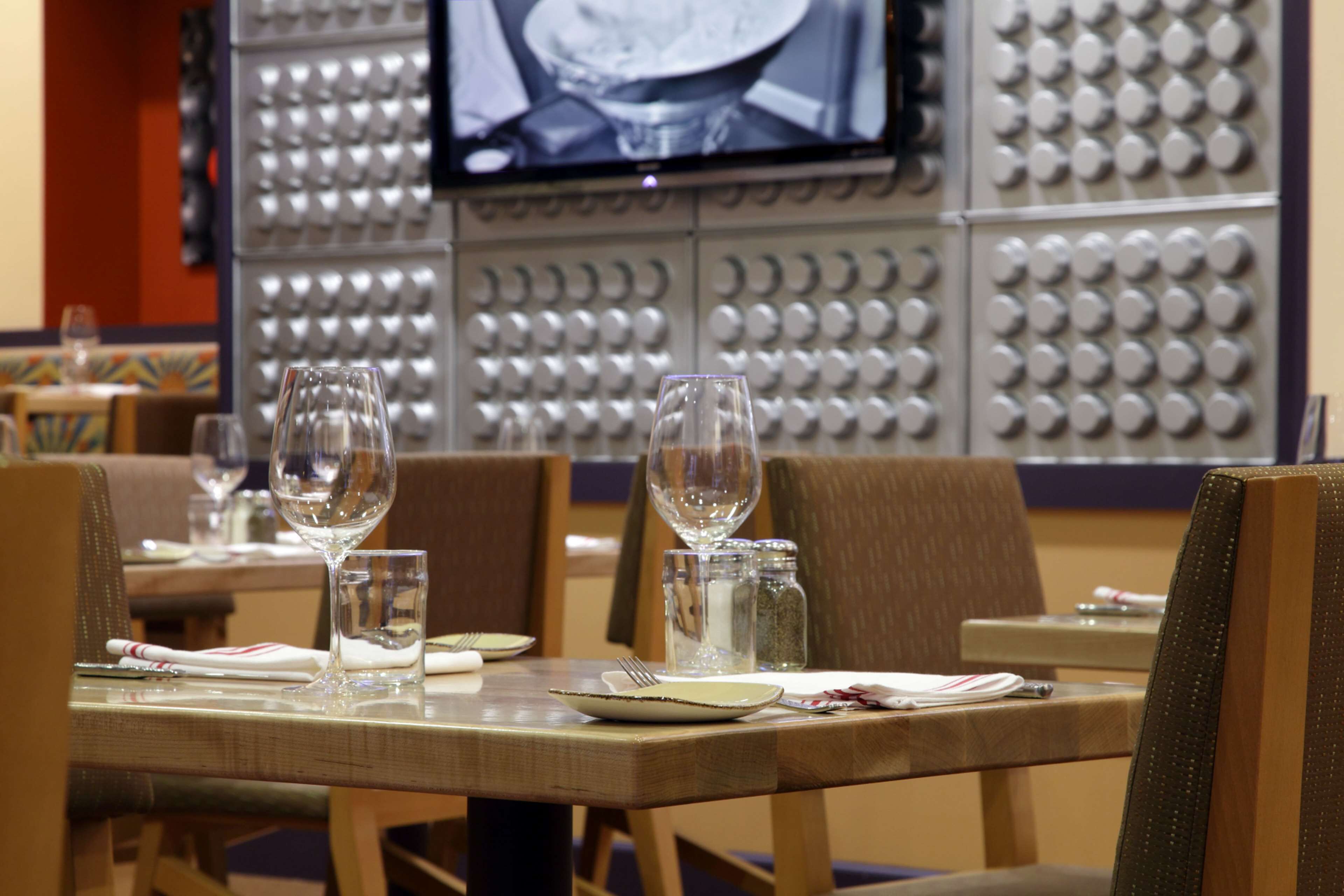A restaurant setting with tables set for dining, including plates, glasses, and cutlery.