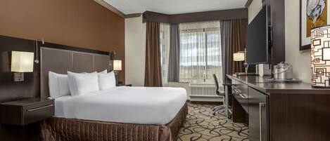 Une chambre d’hôtel avec un grand lit, un bureau, une télévision et une fenêtre avec des rideaux.
