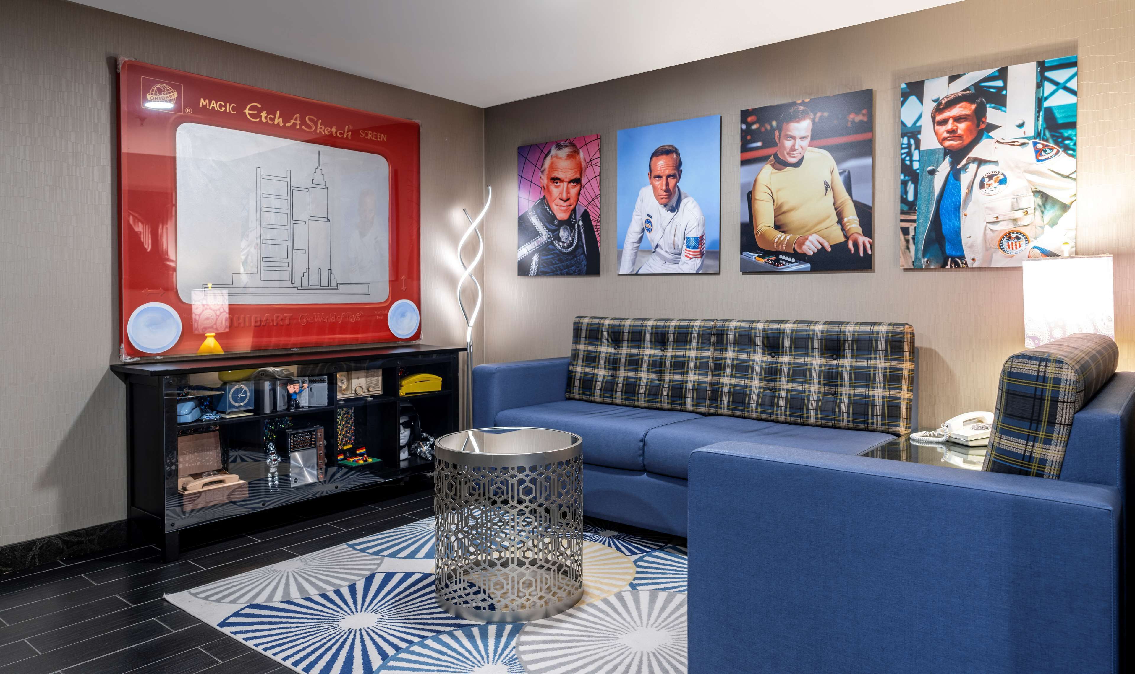A lobby with a blue sofa, a red and white wall art, a metal lamp, and a patterned rug.