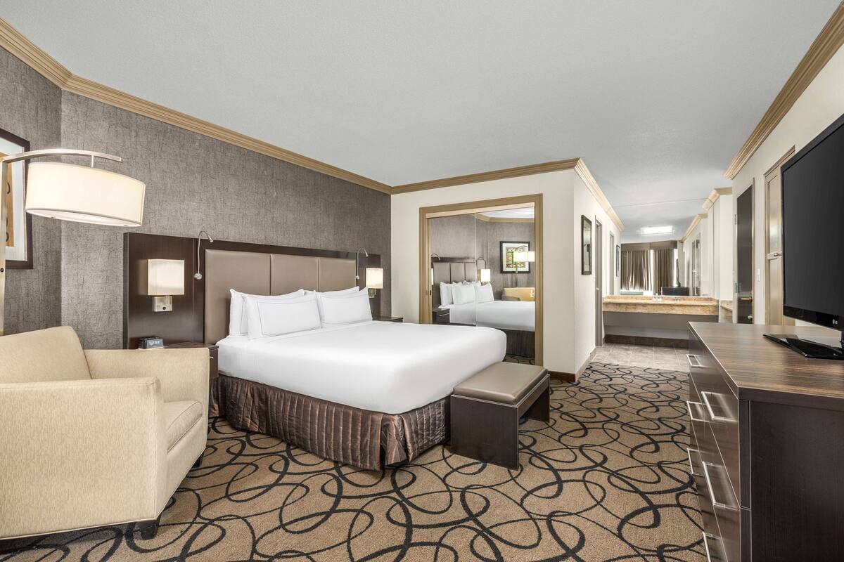 A hotel room with a large bed, a sofa, a desk, and a television.