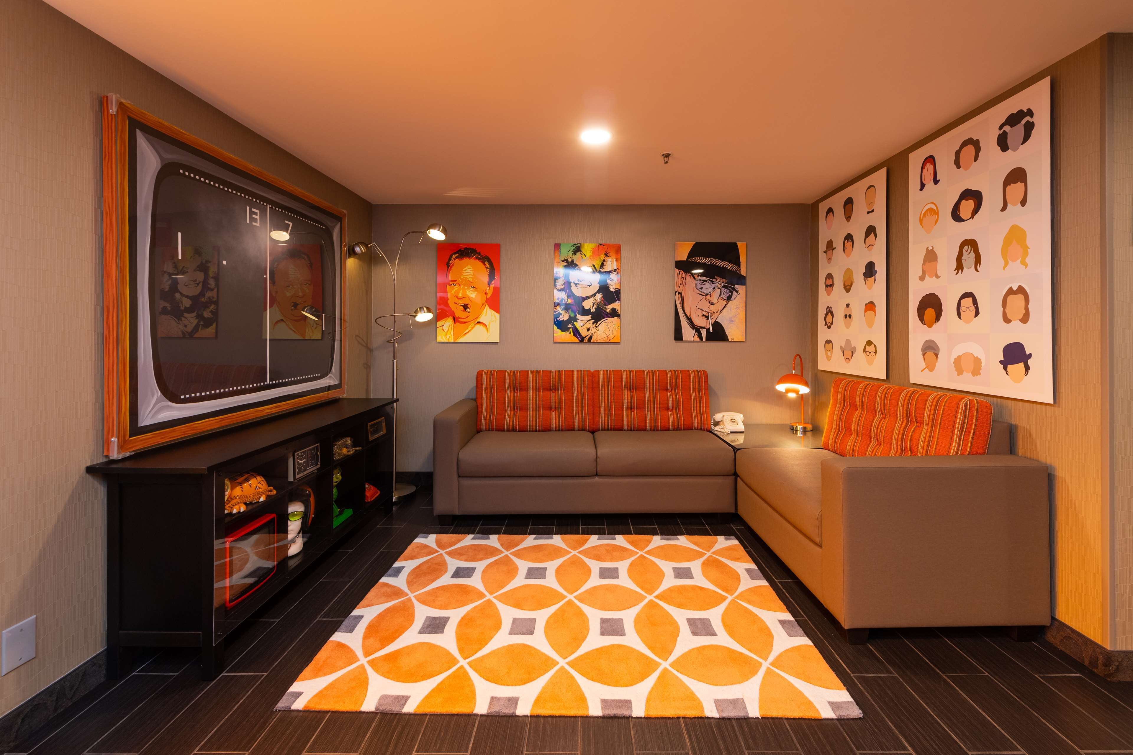 Una sala de estar con un sofá, un televisor y obras de arte en las paredes.