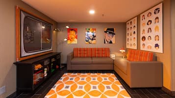 A living room with a sofa, a TV, and artwork on the walls.