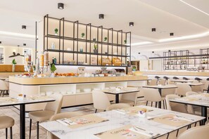 A modern cafe with a central counter, multiple seating areas, and a variety of items on display. - JR Hotels Bologna Gate 7 (Calderara di Reno)
