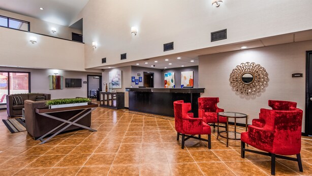 A lobby with a reception desk, red chairs, a sofa, and a large mirror. - Best Western Jacksonville near Little Rock Air Force Base (Jacksonville)
