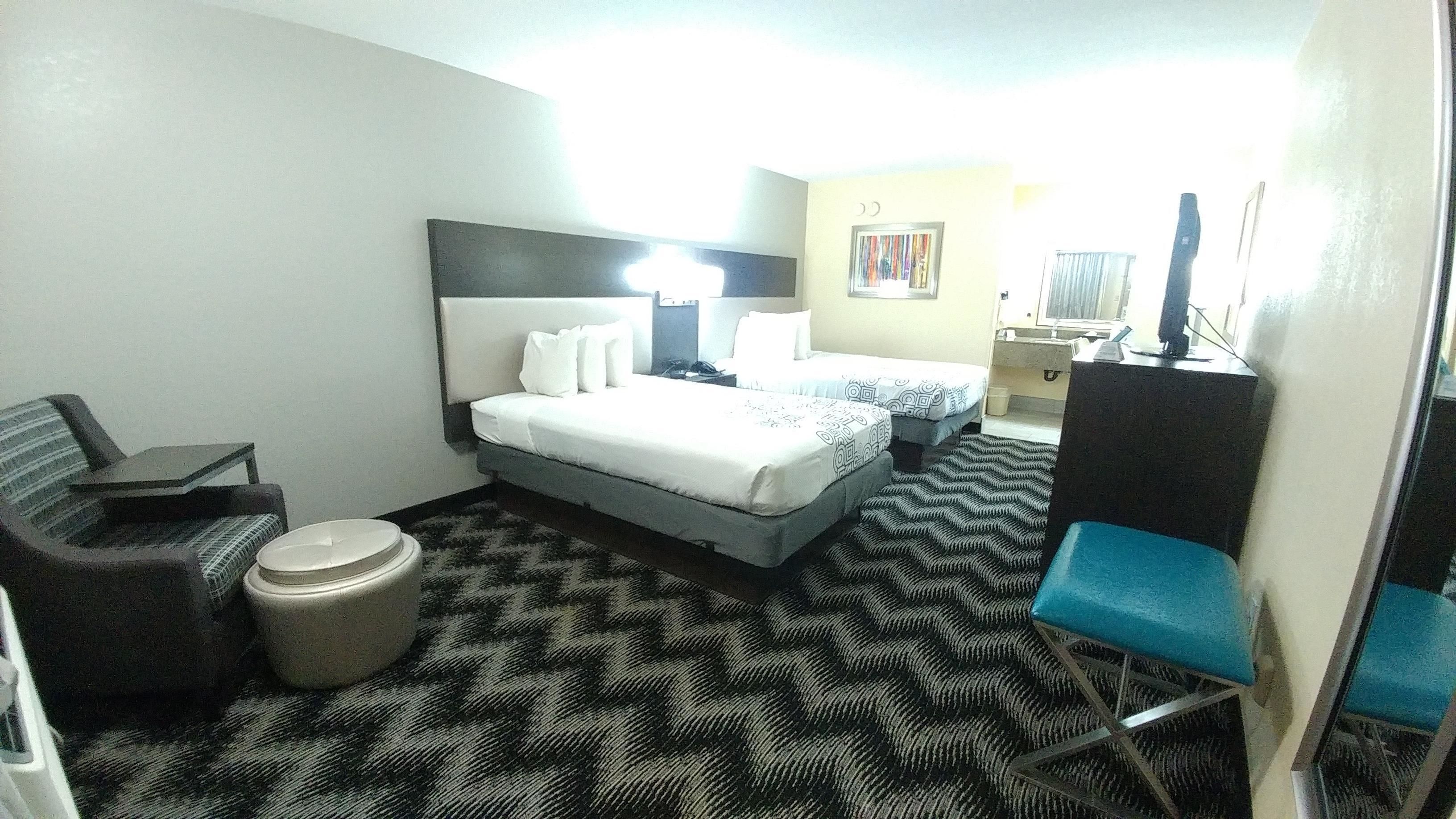 Une chambre d’hôtel comprenant un lit, deux tables de chevet, une chaise, un bureau et une poubelle.