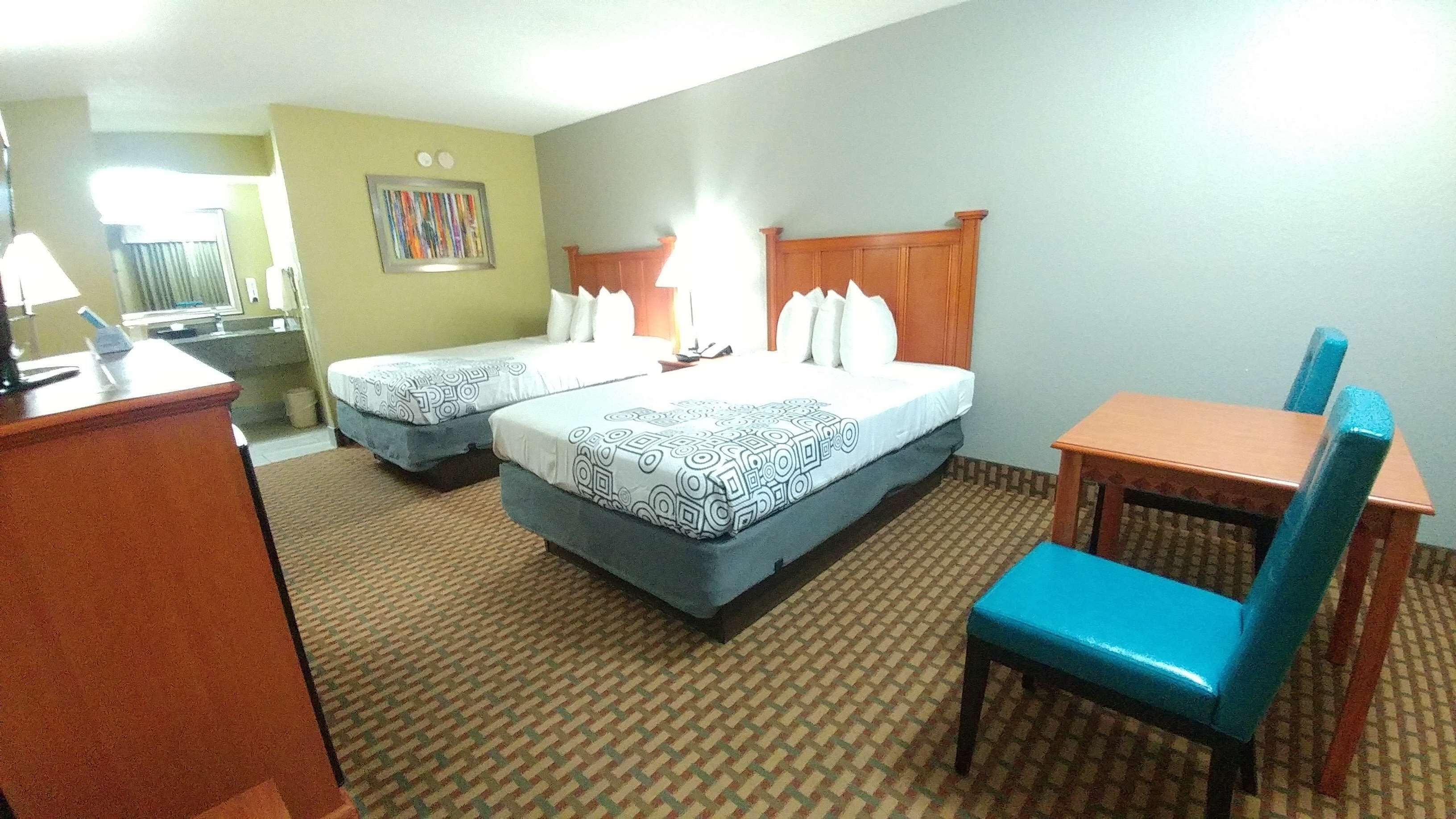 Une chambre d’hôtel avec deux lits, un bureau, une chaise et une petite table.