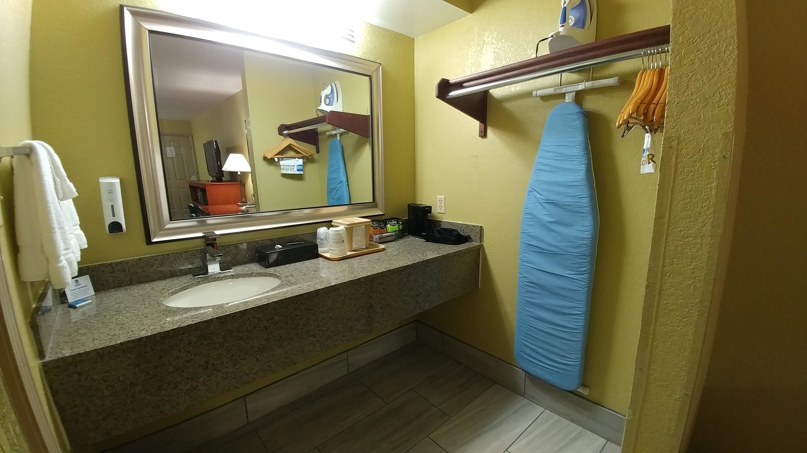 A bathroom with a sink, mirror, towel rack, and shower curtain.