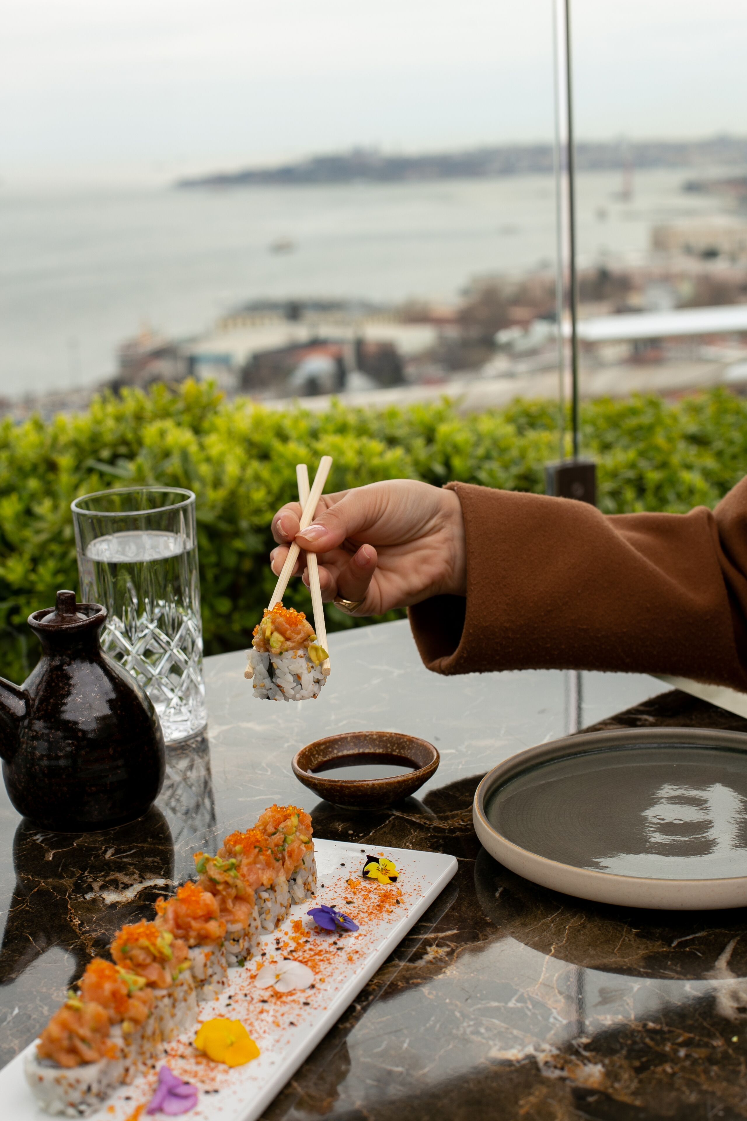 Sashimi på en marmortallerken med et glas vand og en lille skål sauce.