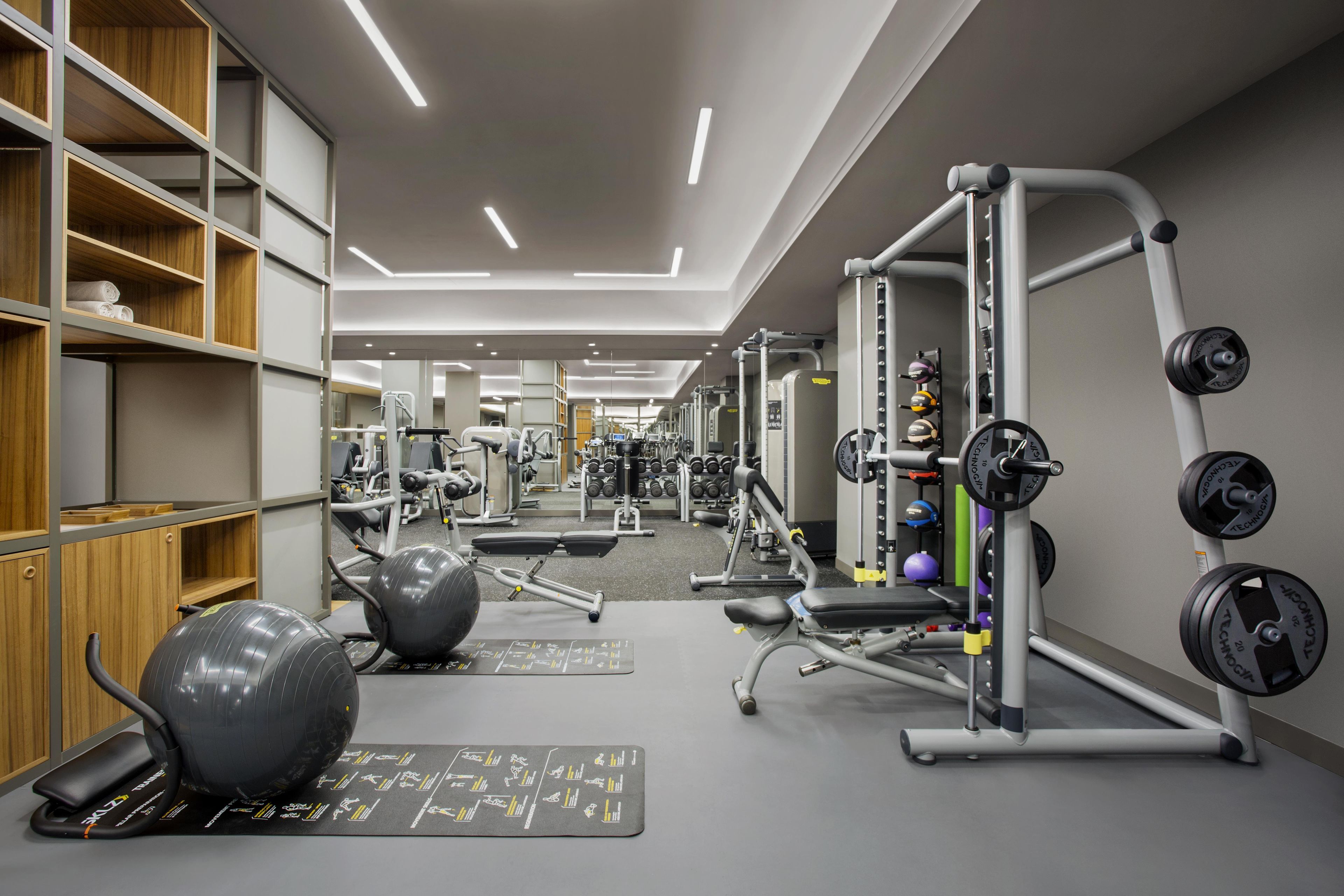 Een moderne sportschool met diverse fitnessapparaten, waaronder een squatrek en losse gewichten.