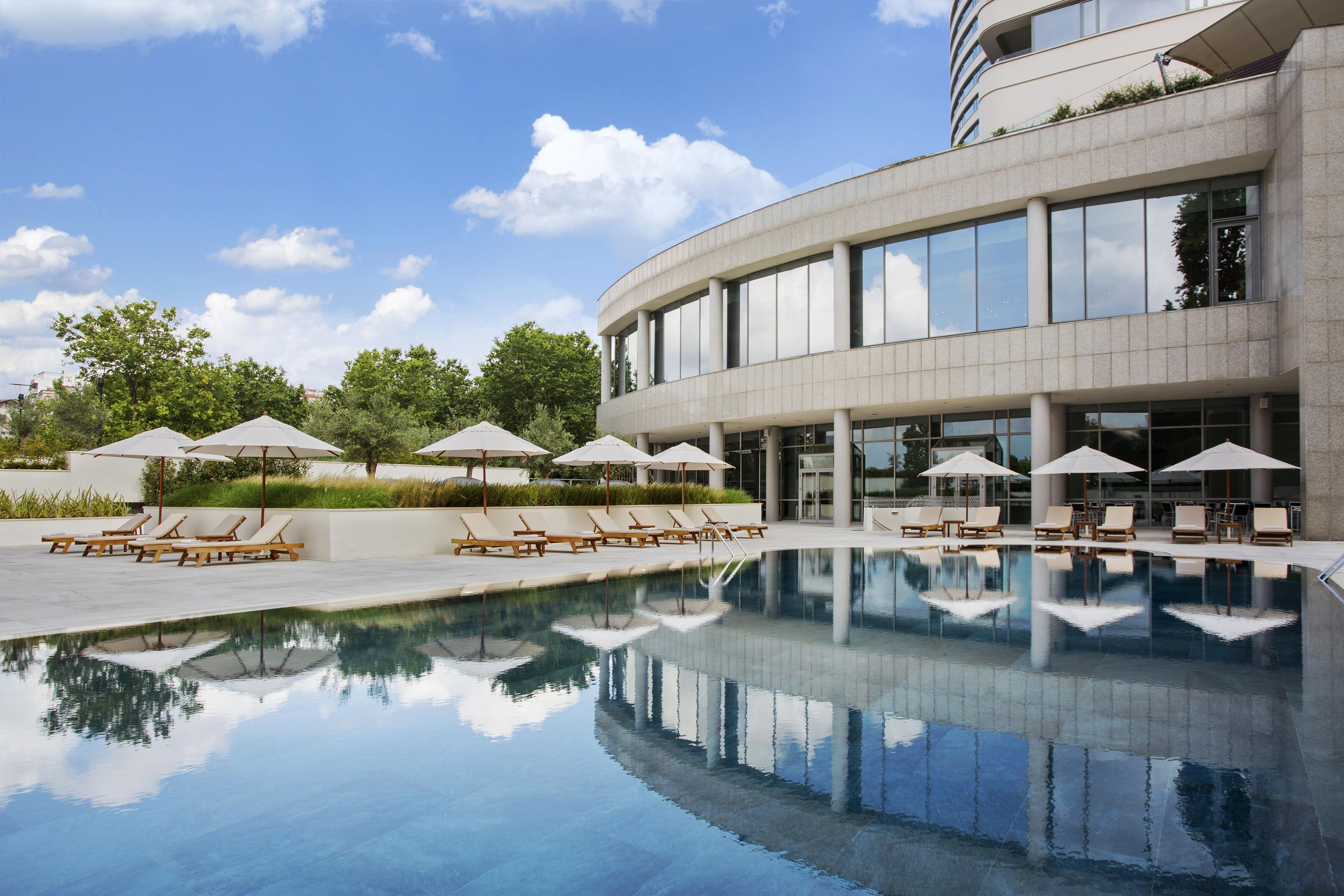 Ein modernes Gebäude mit Schwimmbecken, Liegestühlen und Sonnenschirmen.