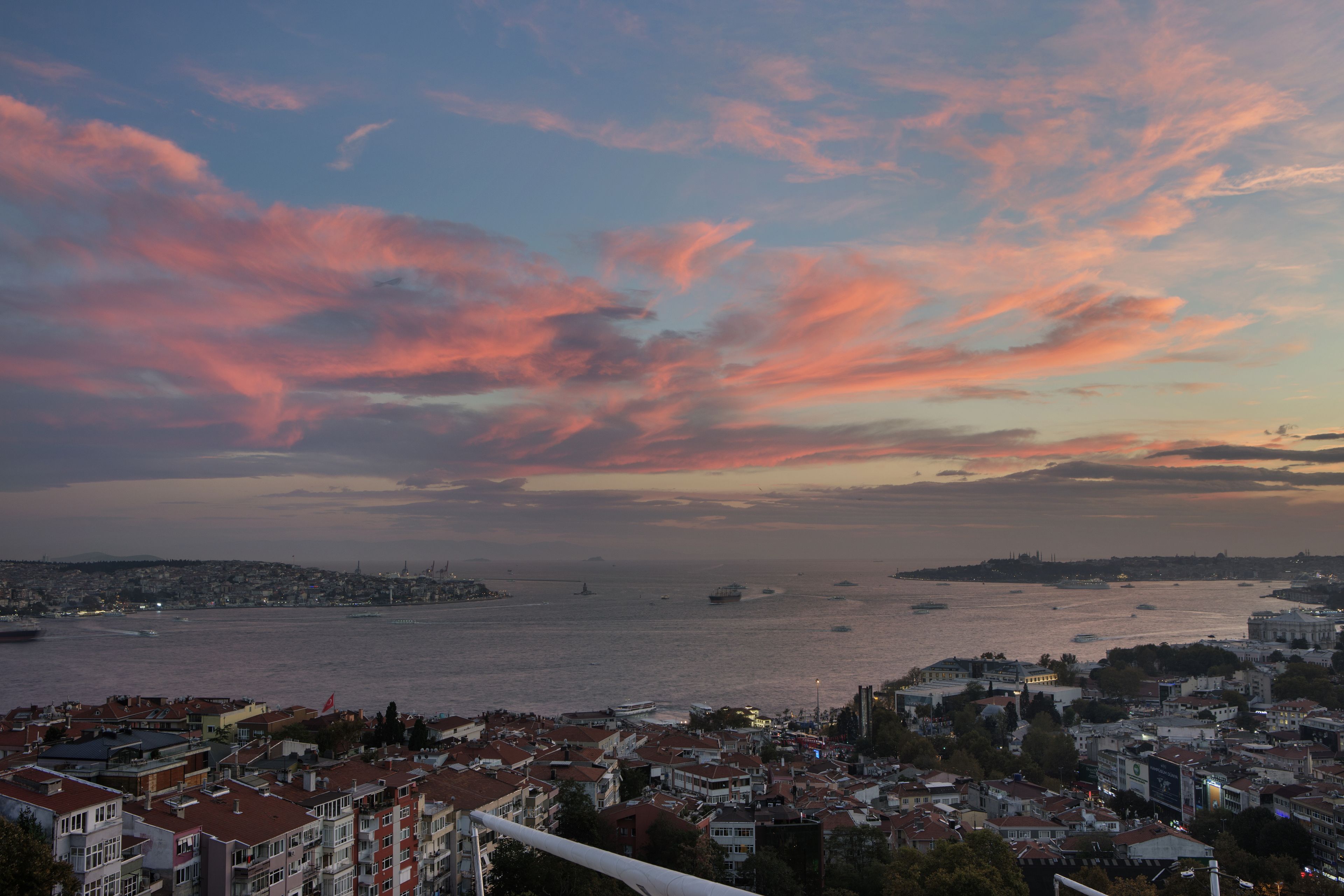 A coastal cityscape with a view of the sea and a sunset sky.