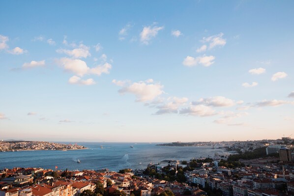 A coastal cityscape with a view of the sea, buildings, and a clear sky.
