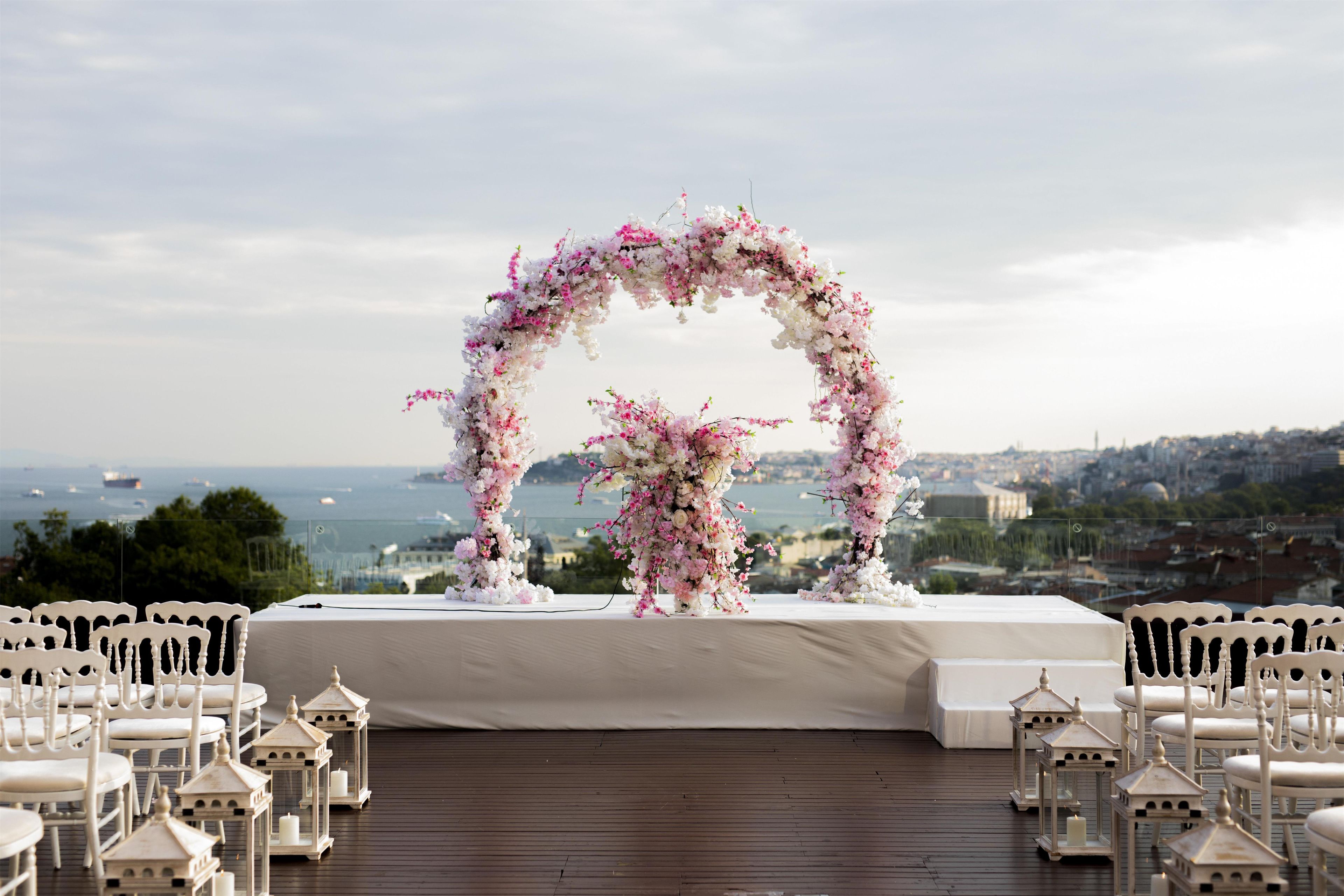 An outdoor wedding ceremony setup with a floral arch and seating.