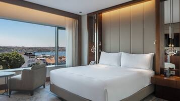 Habitación de hotel moderna con una cama grande, un área de descanso y vistas de la ciudad.