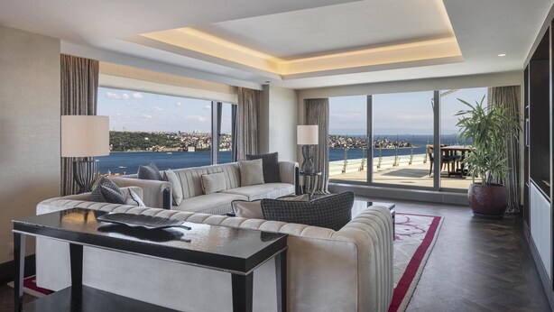 Ein geräumiges Wohnzimmer mit einem großen Fenster, das Meer und Stadtpanorama bietet.