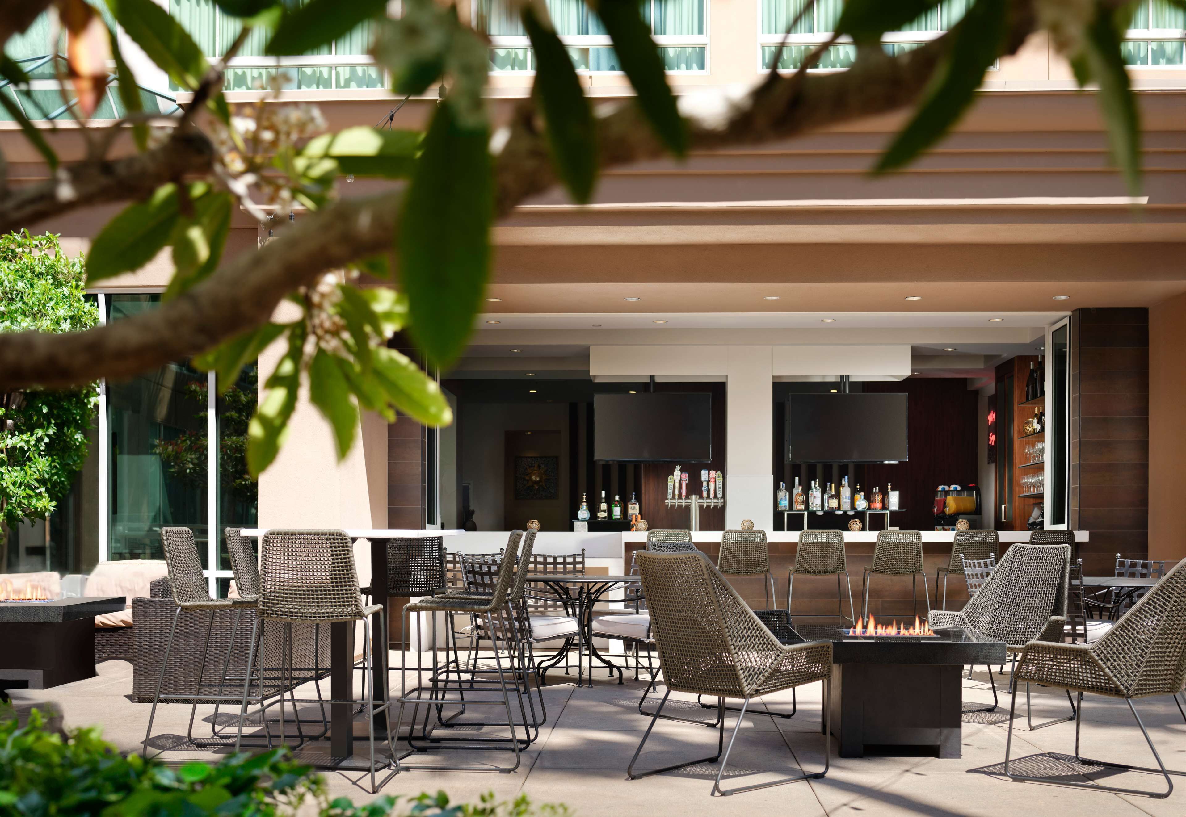 An outdoor patio area with wicker furniture, a bar, and a fire pit.