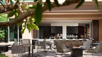 An outdoor patio area with wicker furniture, a bar, and a fire pit.
